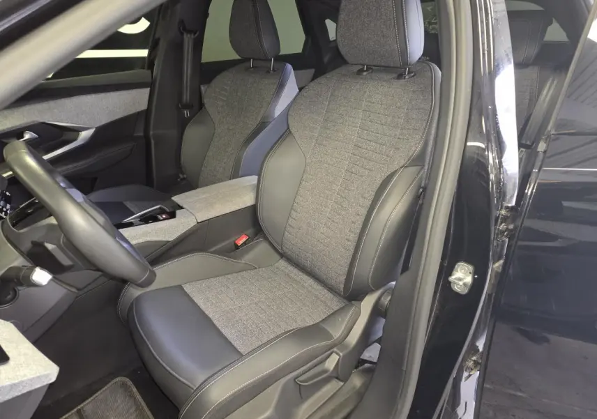 Vue intérieure côté conducteur du Peugeot 3008 2025 noir, sièges tissu gris et cuir noir avec console centrale assortie.