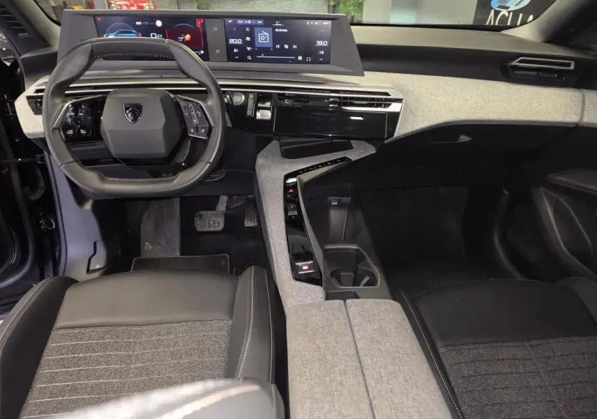 Intérieur avant du Peugeot 3008 2025 noir, vue du conducteur sur le tableau de bord et la console centrale tissu gris et noir.