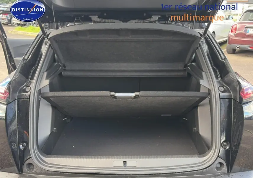 Coffre ouvert en vue arrière d’un Peugeot 2008 noir 2025 avec cache-bagages et hayon relevé.