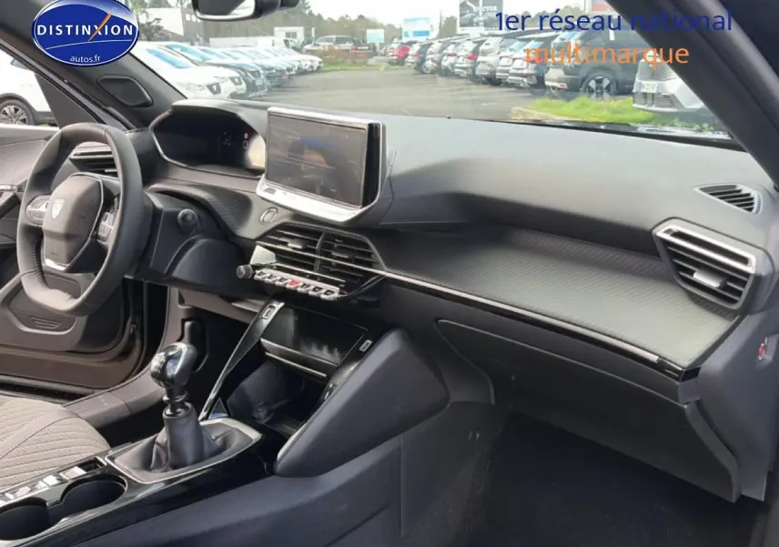 Vue intérieure côté passager du tableau de bord noir du Peugeot 2008 1.2 100 allure avec écran tactile et levier de vitesse manuel.