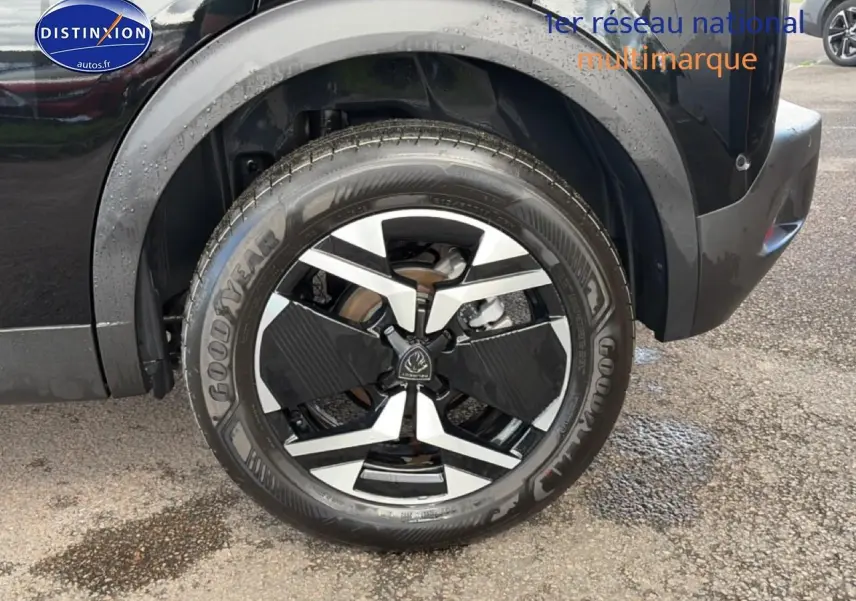 Gros plan sur la roue arrière droite noire d'une Peugeot 2008 1.2 100 allure avec jante alu bicolore.