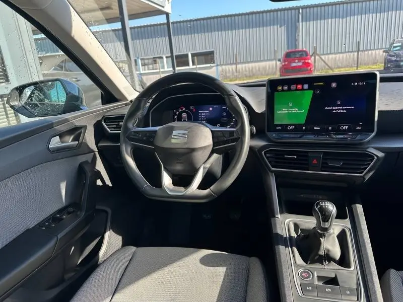 Vue intérieure avant centrée sur le volant multifonction et l'écran tactile du tableau de bord du SEAT LEON ST 2025.