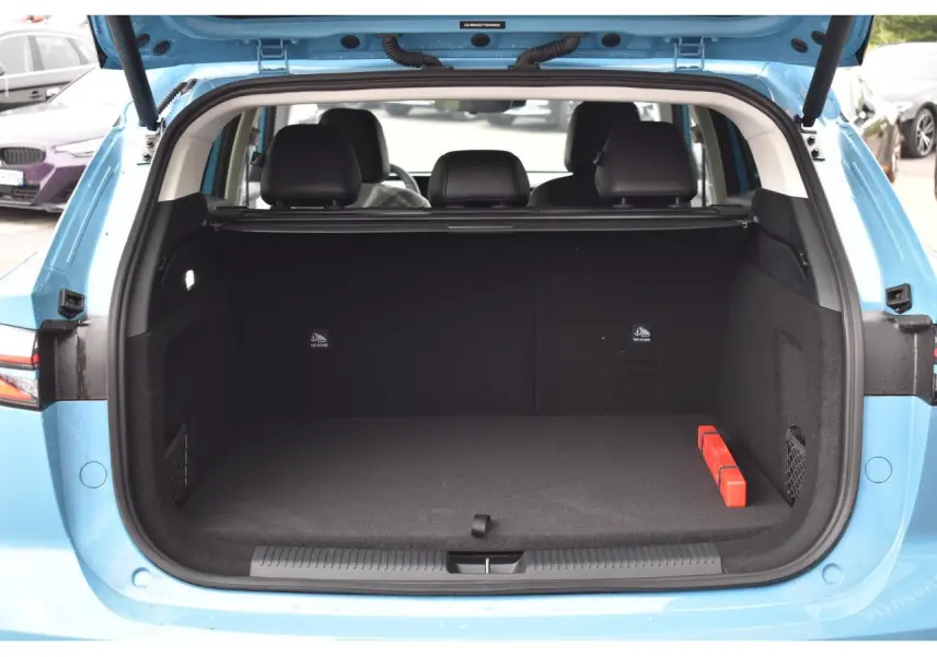 Coffre ouvert vu de l'arrière d'un MG Motor EHS bleu 2026, avec banquette arrière et tapis noir visible.