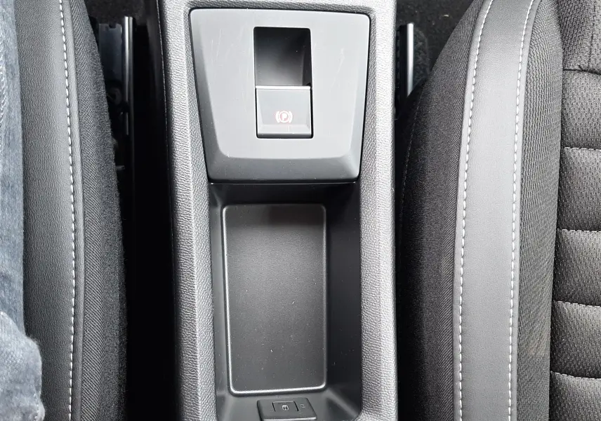 Vue plongeante sur la console centrale noire du Citroën C3 Aircross 1.2 Hybrid 145ch, avec frein à main électronique et accoudoirs.