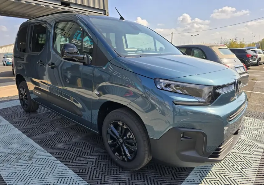 Vue 3/4 avant droite d'un Citroën Berlingo 2025 bleu Kiama métallisé avec jantes aluminium noires et barres de toit.