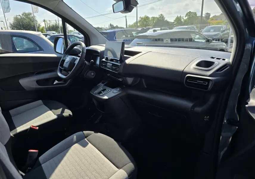 Intérieur avant du Citroën Berlingo bleu Kiama, vue côté conducteur montrant tableau de bord et sièges gris bicolores.