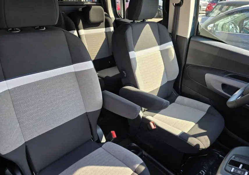 Vue intérieure rapprochée des sièges avant gris et noirs du Citroën Berlingo 2025 avec accoudoir central côté droit.