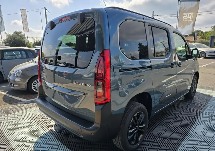 Vue 3/4 arrière droite du Citroën Berlingo bleu Kiama métallisé avec vitres arrière teintées et jantes noires.