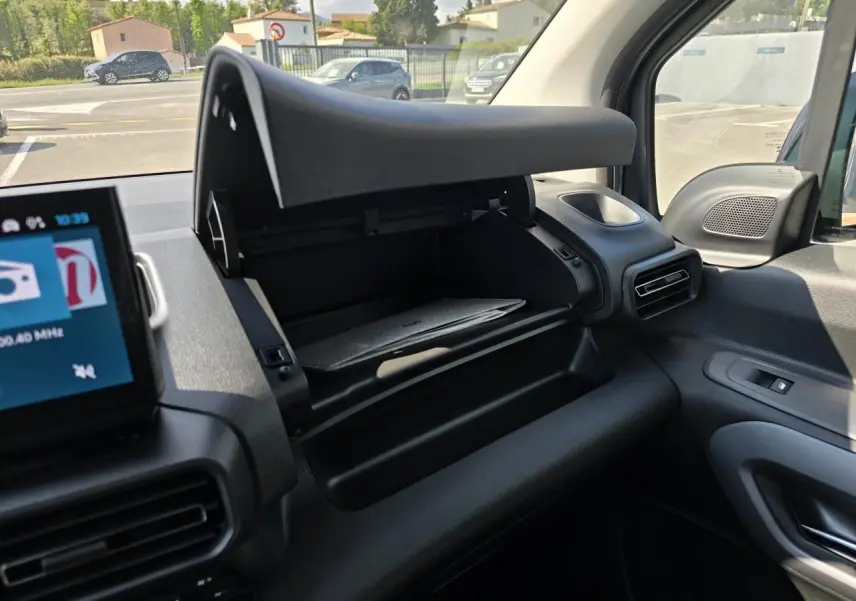 Vue intérieure côté passager du Citroën Berlingo 2025 bleu Kiama, boîte à gants ouverte et tableau de bord noir.