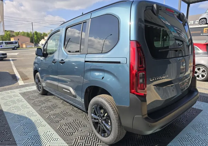 Vue 3/4 arrière droite du Citroën Berlingo bleu Kiama métallisé avec vitres arrière teintées et jantes aluminium noires.