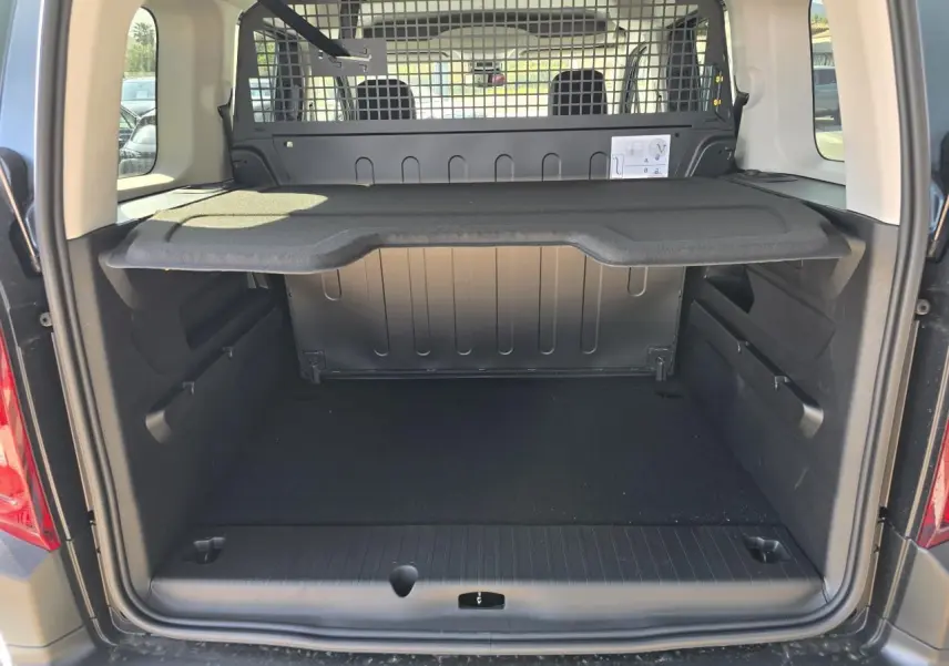 Coffre ouvert vu de l'arrière du Citroën Berlingo III Bleu Kiama Métal avec séparation grillagée et tablette de rangement.