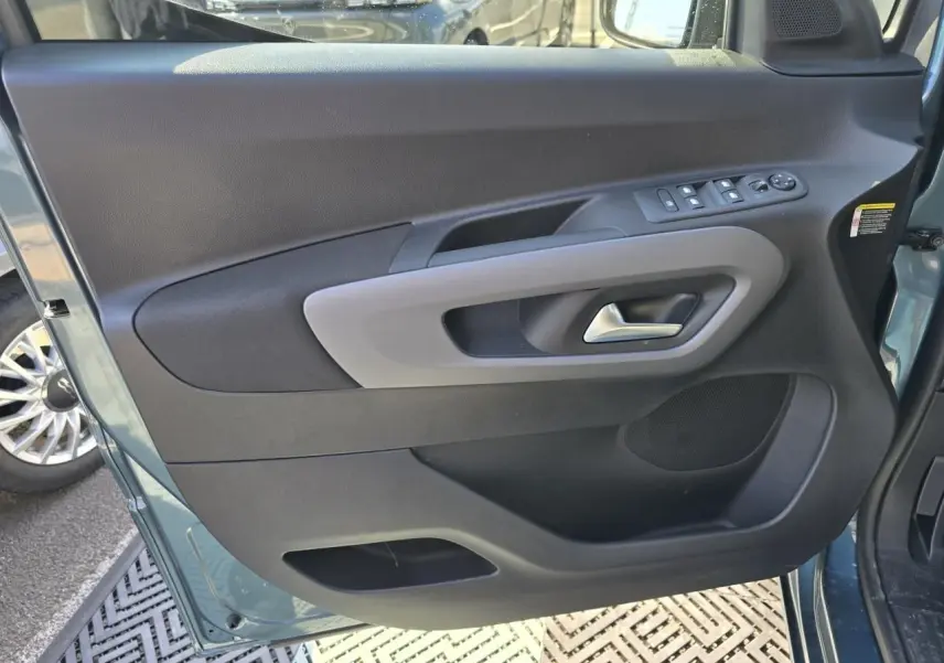 Vue rapprochée de la porte avant gauche bleu Kiama métallisé du Citroën Berlingo 2025 avec commandes de vitres et poignée grise.