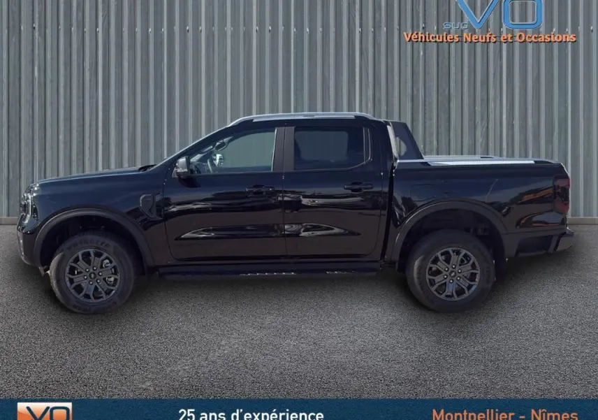 Profil latéral gauche du Ford Ranger noir double cabine avec jantes alliage 18 pouces et barres de toit visibles.