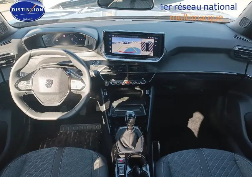 Vue intérieure avant de la Peugeot 2008 gris artense 2025, volant multifonction et écran tactile avec caméra de recul.
