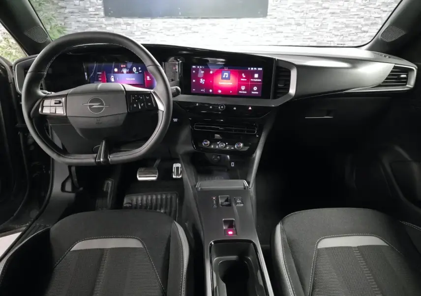 Vue intérieure avant de l’Opel Mokka-e 2025 noire, tableau de bord digital et écran tactile central lumineux.