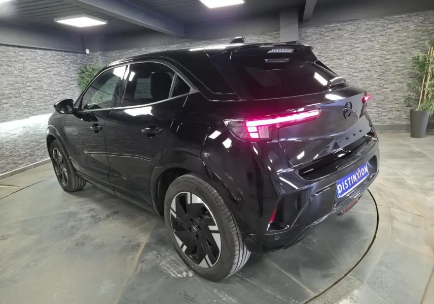 Vue 3/4 arrière droite de l'Opel Mokka-e 2025 noire avec feux arrière LED et jantes alliage 18 pouces.