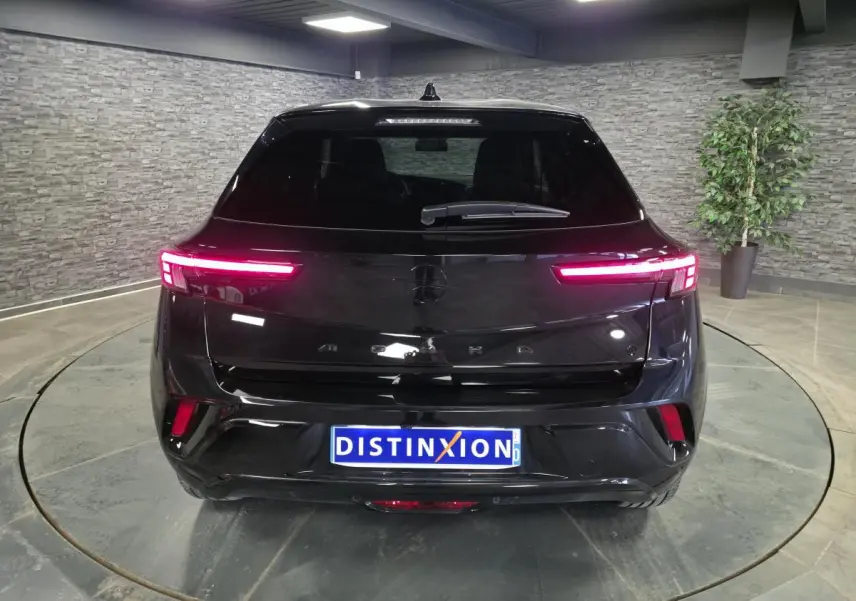 Vue arrière d'un Opel Mokka-e noir avec feux arrière LED allumés dans un showroom intérieur.