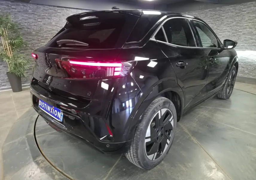 Vue 3/4 arrière droite de l'Opel Mokka-e noir avec feux arrière LED allumés et jantes alliage 18 pouces.