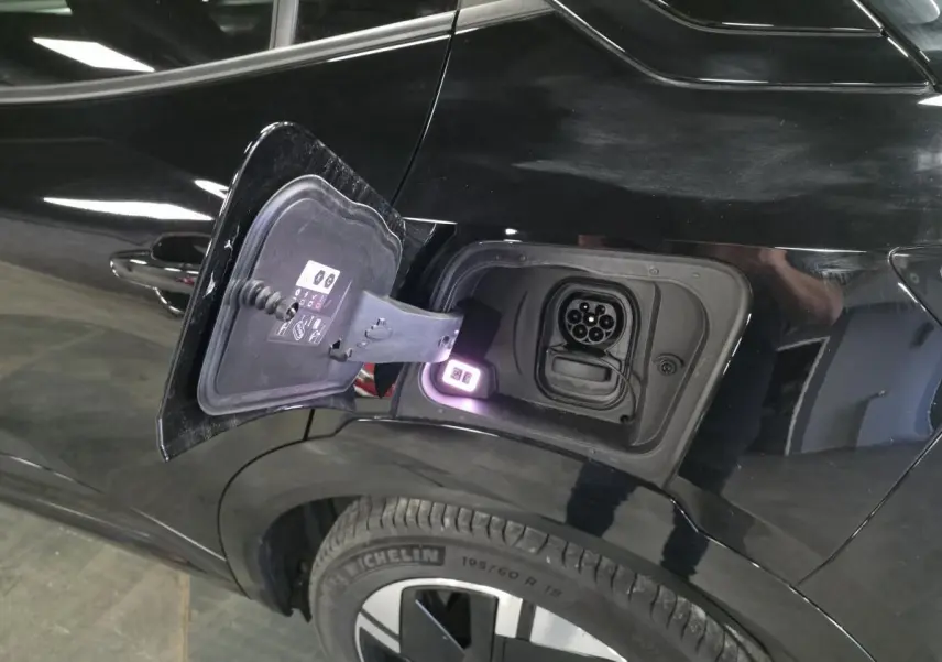 Vue côté gauche arrière d'un Opel Mokka-e noir avec trappe de recharge électrique ouverte et prise visible.