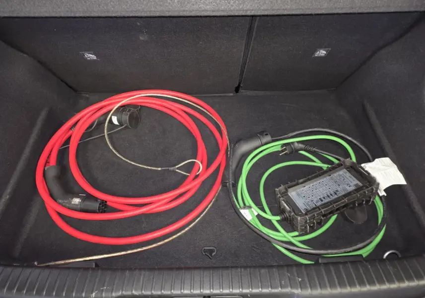 Coffre ouvert d’Opel Mokka-e noir, vue de dessus montrant câbles de recharge rouge et vert rangés.