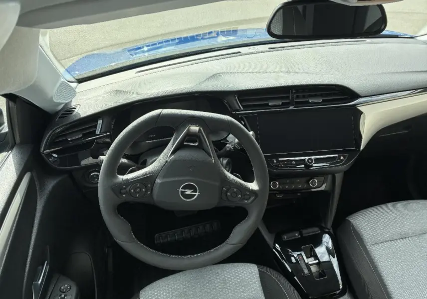 Intérieur de l’Opel Corsa 2025 en gris kristall, vue du poste de conduite avec volant multifonction et écran tactile central.