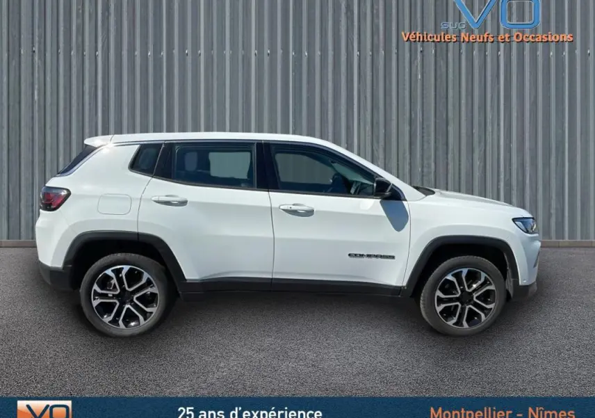 Profil côté gauche d'un Jeep Compass blanc 2024 avec jantes alliage 18 pouces sur fond industriel.