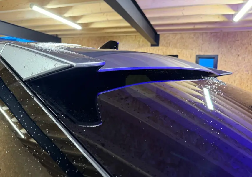 Détail de l'aileron arrière gris du Peugeot 3008 1.2 Hybrid 136 Allure, vu de près sous un éclairage intérieur.