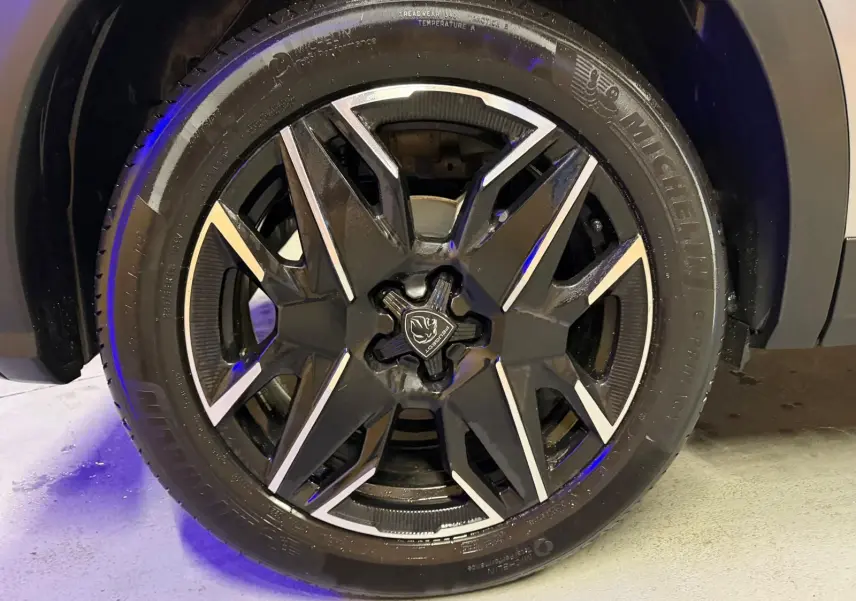 Gros plan sur la jante noire et argentée du Peugeot 3008 gris, mettant en valeur le logo central et le pneu Michelin.