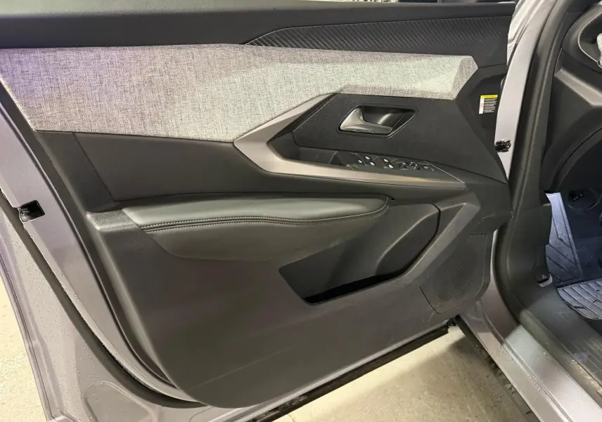 Vue rapprochée de la porte avant gauche grise du Peugeot 3008 1.2 Hybrid 136 Allure avec habillage tissu et commandes électriques.