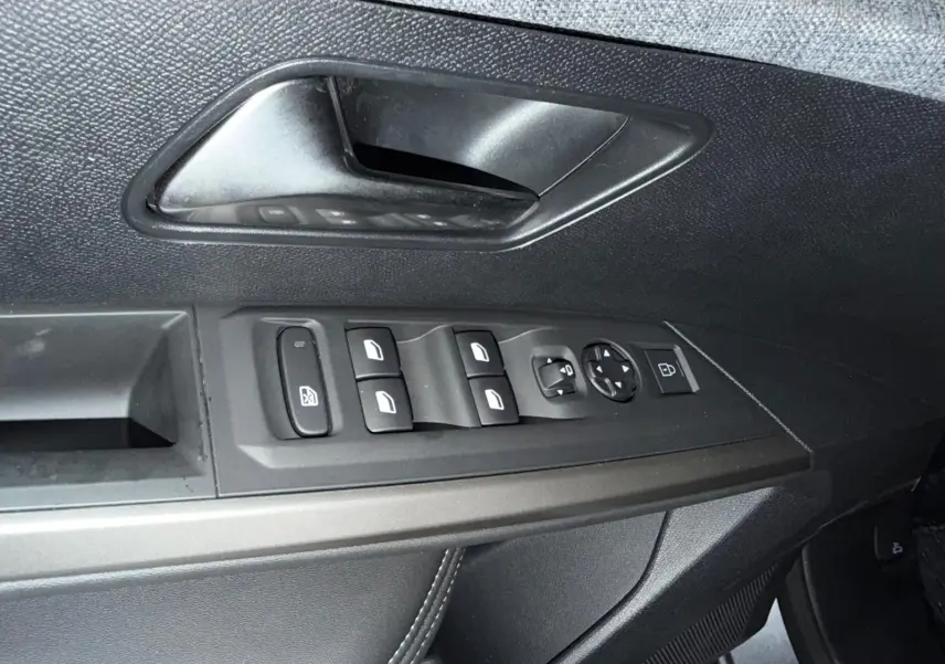 Gros plan sur la commande des vitres électriques et la poignée intérieure côté gauche du Peugeot 3008 gris 1.2 HYBRID 136 ALLURE.