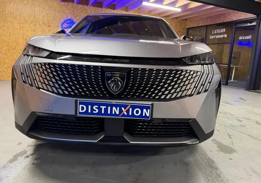 Vue avant rapprochée du Peugeot 3008 gris 1.2 HYBRID 136 Allure avec calandre distinctive et logo lion central.