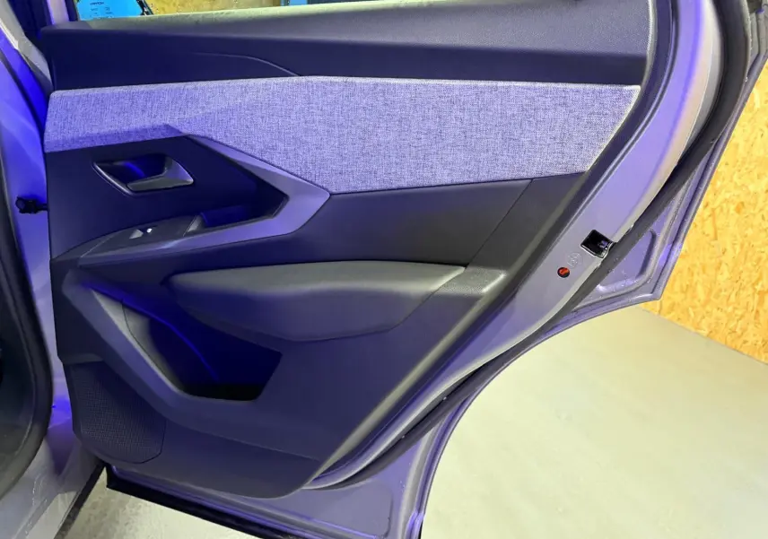 Vue rapprochée de la porte arrière gauche gris clair du Peugeot 3008 1.2 HYBRID 136 Allure avec habillage tissu et plastique noir.