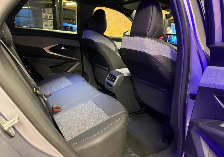 Vue intérieure côté arrière droit du Peugeot 3008 gris 2025, montrant les sièges arrière en tissu et cuir bicolore.