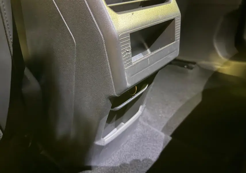 Détail de la console arrière noire du Peugeot 3008 1.2 Hybrid 136 Allure, avec rangement et prise visible.