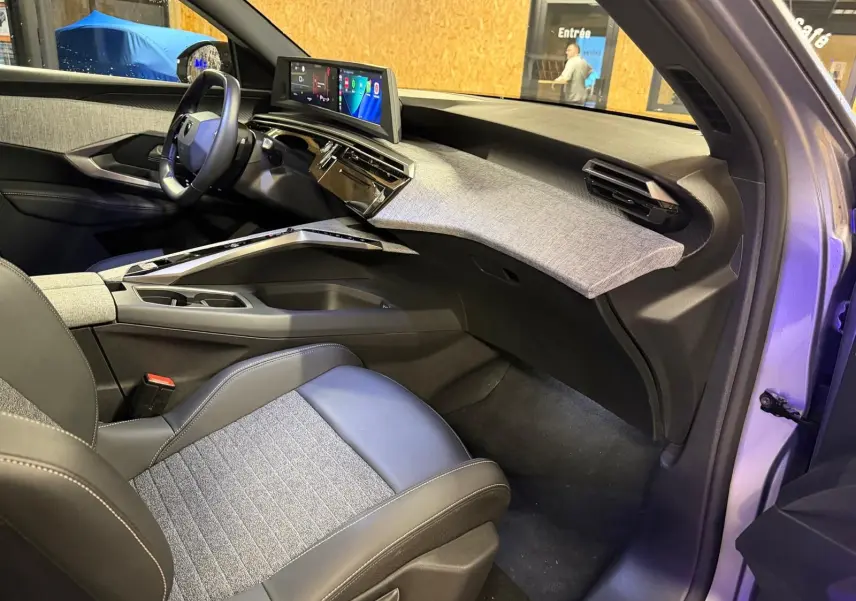 Vue intérieure côté passager du Peugeot 3008 1.2 Hybrid 136 Allure gris, avec tableau de bord moderne et sellerie tissu noir et gris.