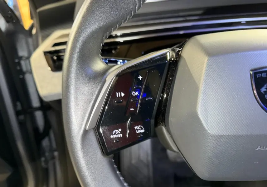 Gros plan sur les commandes gauche du volant gris du Peugeot 3008 1.2 Hybrid 136 Allure, intérieur noir.