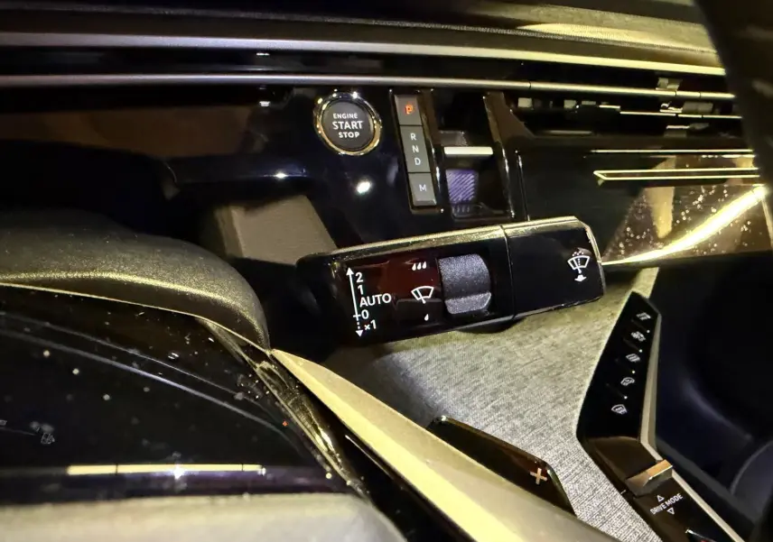 Détail intérieur du tableau de bord du Peugeot 3008 gris, avec bouton start/stop et commande essuie-glace.