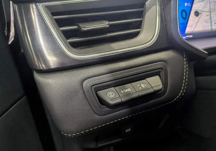 Gros plan sur les commandes à gauche du tableau de bord du Renault Symbioz gris Cassiopé, avec boutons E-SAVE et réglage phares.