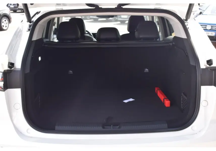 Coffre ouvert d’un MG Motor EHS blanc, vue arrière, montrant l’espace de chargement vide avec un triangle de signalisation rouge.