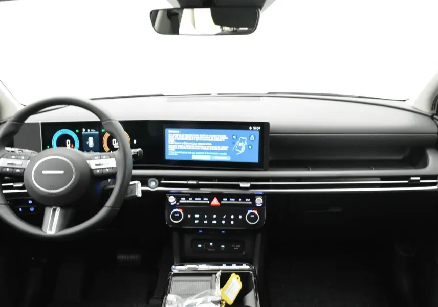 Vue intérieure avant du Hyundai Tucson 2025, tableau de bord noir avec écran tactile large et volant multifonction.