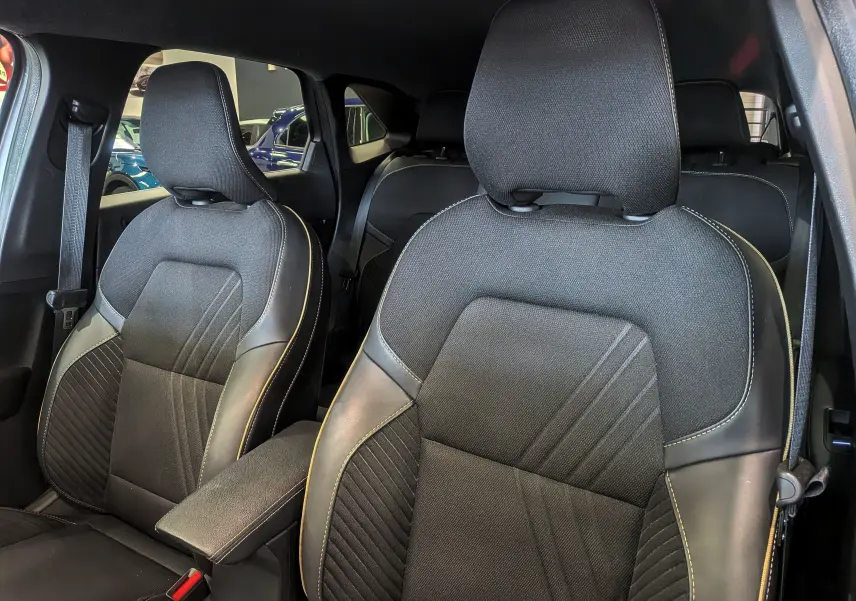 Vue rapprochée des sièges avant en tissu et cuir noir avec surpiqûres claires dans l’habitacle du Renault Symbioz 2025.