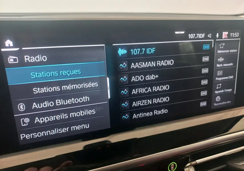 Écran tactile central du tableau de bord du BMW X3 xDrive30e 2022 affichant les stations radio DAB.