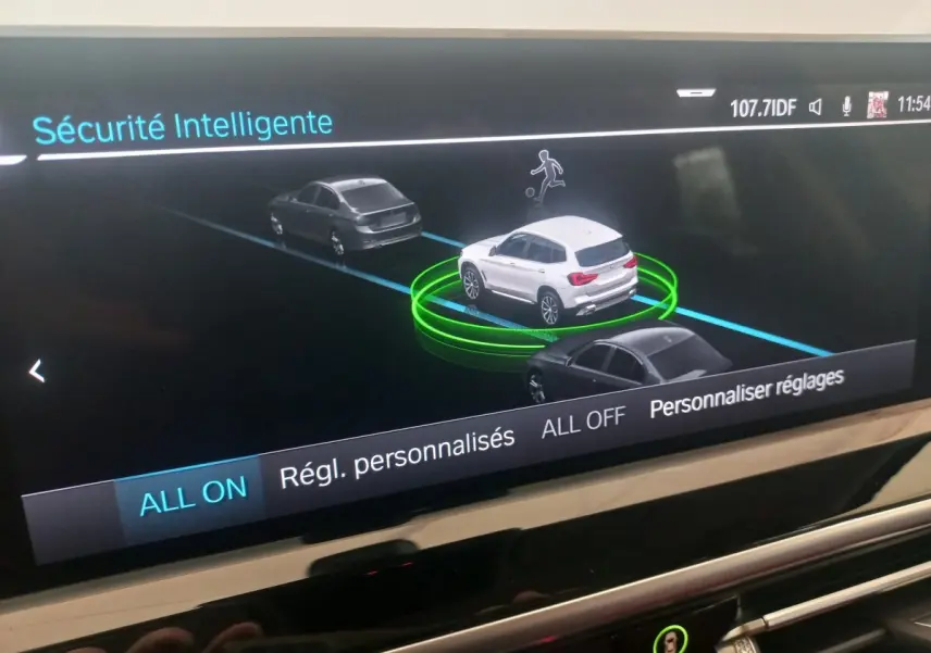 Affichage intérieur BMW X3 blanc vu de 3/4 arrière sur écran de sécurité intelligente avec véhicules gris autour.