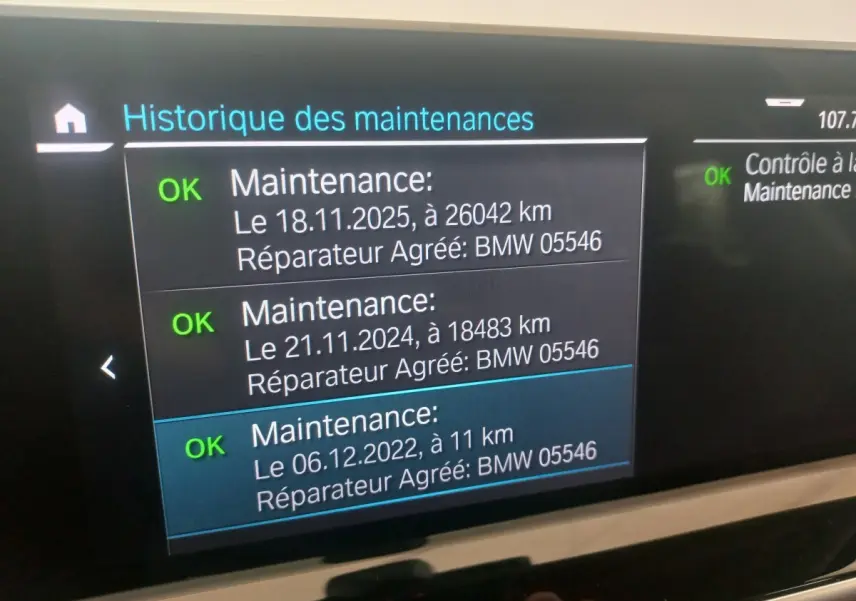 Écran central tactile affichant l'historique des maintenances du BMW X3 xDrive30e blanc, vue intérieure.