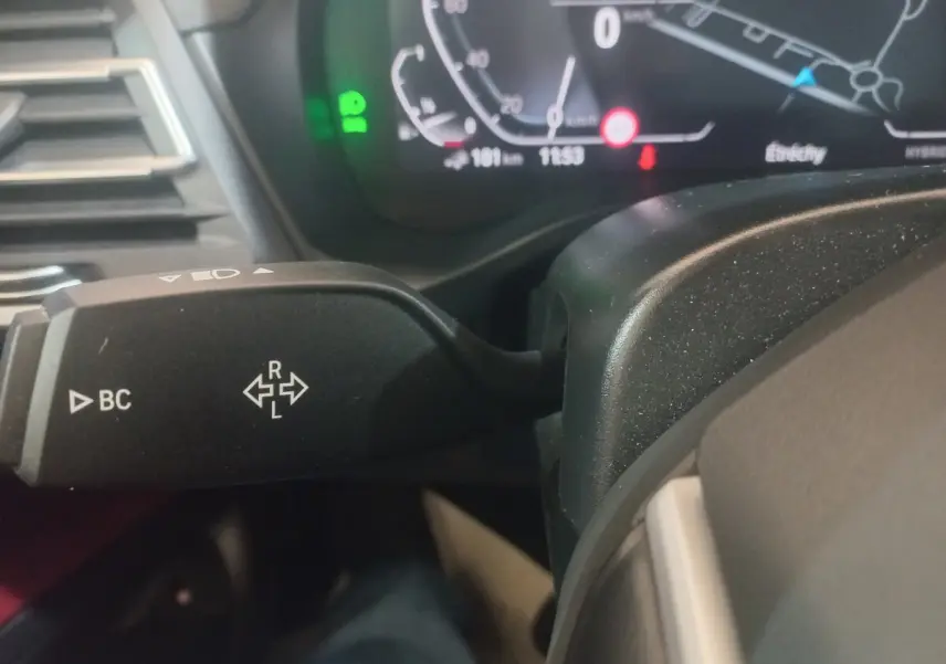 Gros plan sur la manette de clignotant gauche du tableau de bord du BMW X3 blanc, avec affichage digital en arrière-plan.