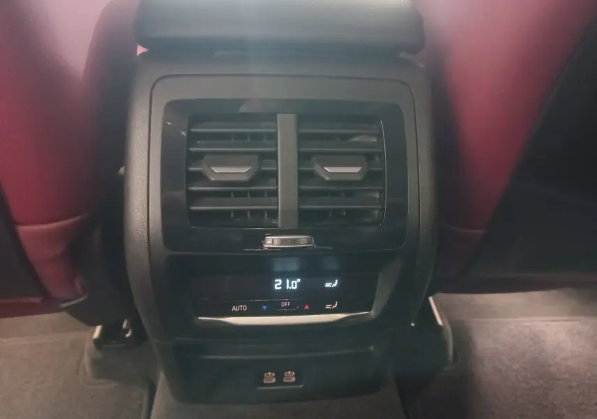 Vue rapprochée de la console arrière avec sorties d’air et commandes climatisation digitale du BMW X3 blanc 2022.