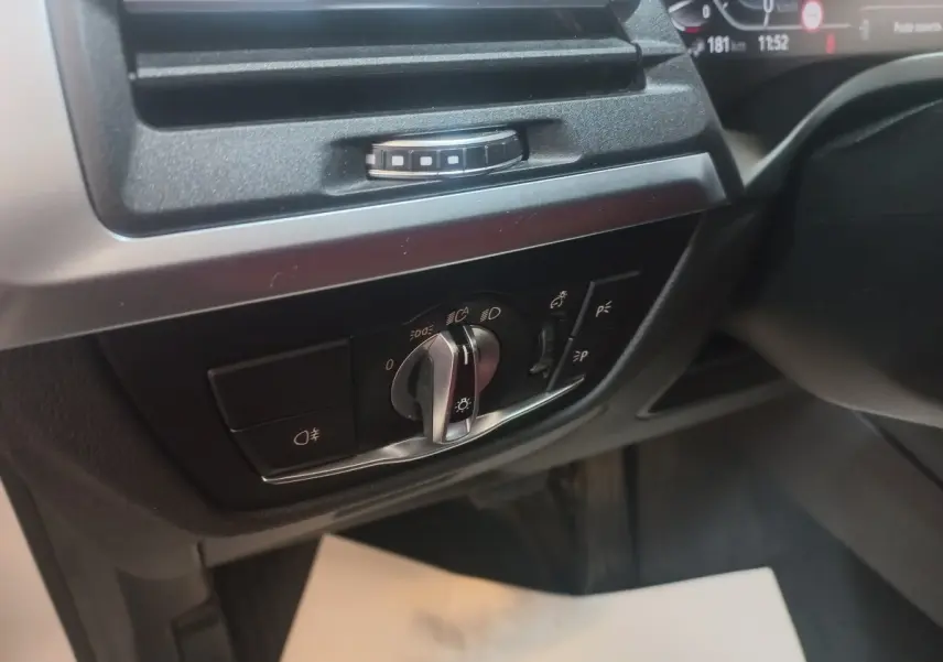 Gros plan sur le panneau de commande des phares et éclairages intérieurs dans l'habitacle du BMW X3 blanc xDrive30e.