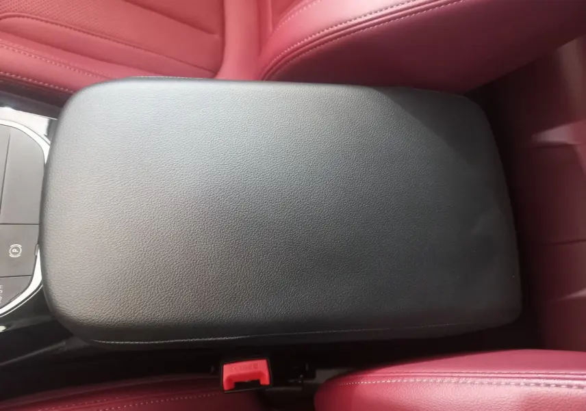 Accoudoir central noir entouré de sièges en cuir rouge dans l'habitacle du BMW X3 xDrive30e blanc 2022.