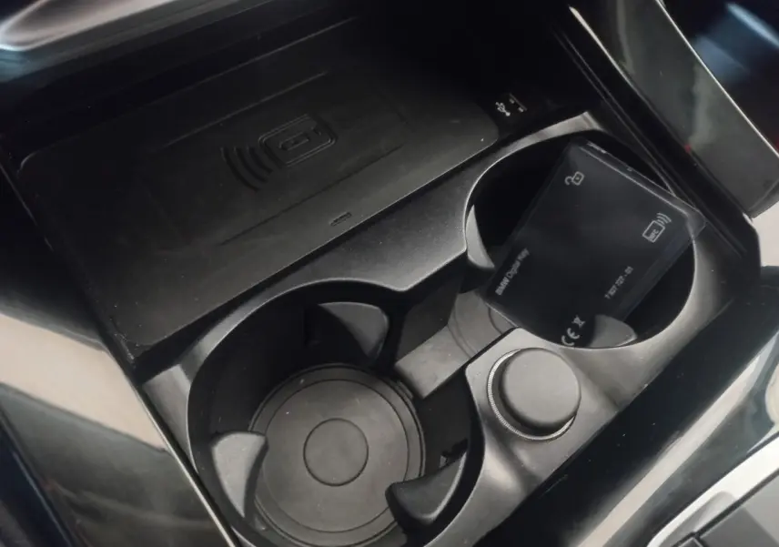 Gros plan sur la console centrale noire du BMW X3 xDrive30e 2022, avec porte-gobelets et zone de charge sans fil.