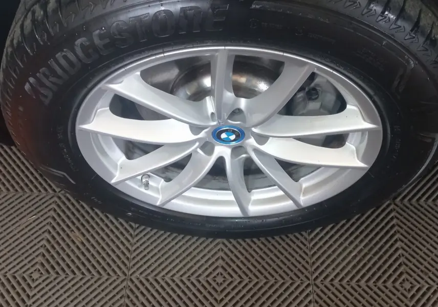 Gros plan sur la jante argentée avec logo BMW au centre, montée sur pneu Bridgestone noir.